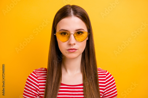 Closeup portrait photo of pretty calm concentrated young girl self-assured look prepare argue parents want home party wear sun specs striped white red shirt vivid yellow color background