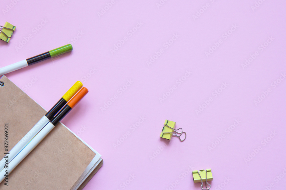 Set of stationery items on pink background. Notebook and colorful pencils, clips. Flat lay Set of stationery items on pink background. Notebook and colorful pencils, clips. Flat lay