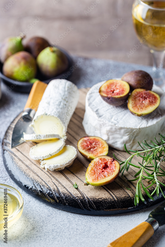 Fresh goat brie cheese with truffle and white mold on cheese platter with figs and honey Fresh goat brie cheese with truffle and white mold on cheese platter with figs and honey