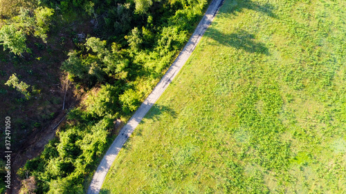 Vista aerea dal drone di una strada di campagna in mezzo a campi e prati con ombre di alberi