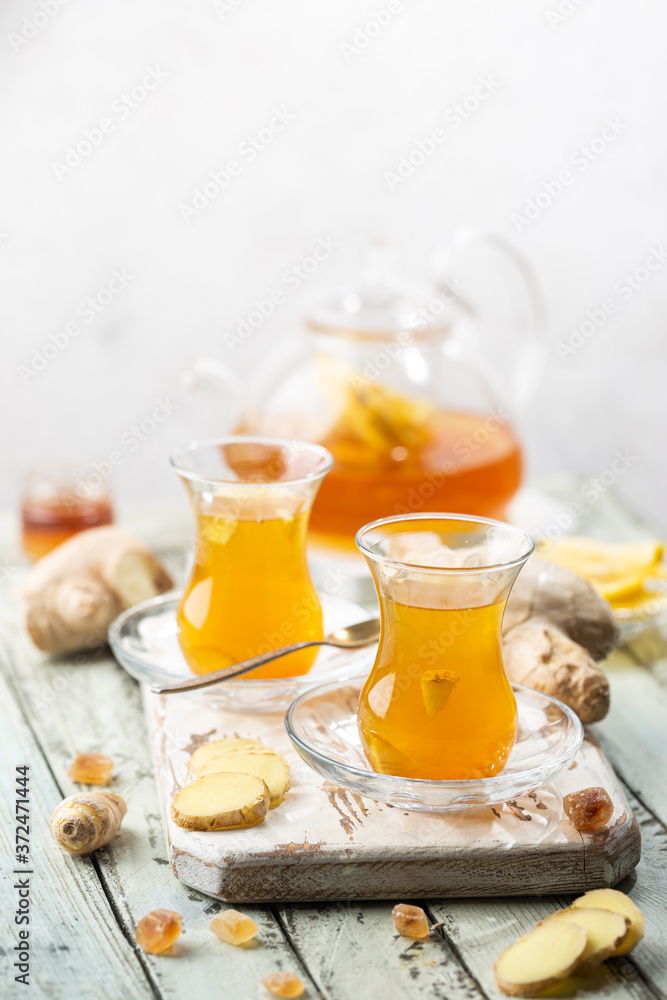 Ginger tea in a glass cup with lemon and mint on light background Ginger tea in a glass cup with lemon and mint on light background
