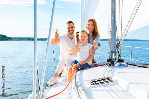 Family Gesturing Thumbs-Up Sitting On Deck Sailing Across Sea Outside © Prostock-studio