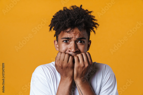Image of scared african american guy biting his fingernails © Drobot Dean