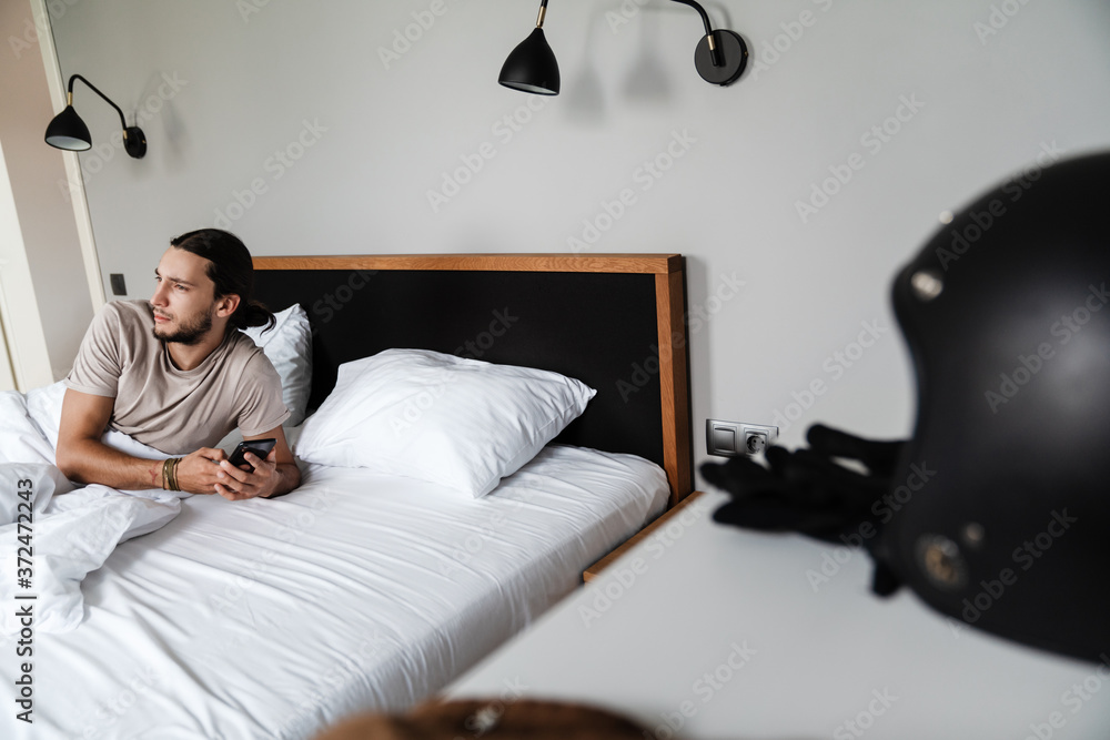 Fototapeta premium Smiling young man using mobile phone