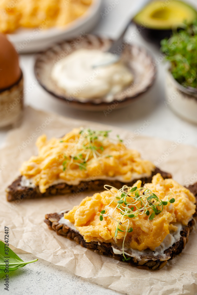 Scrambled egg sandwich with cream cheese on rye toast for breakfast on white background. Healthy breakfast or snack