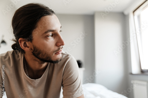 Young man in depression sitting on bed photo