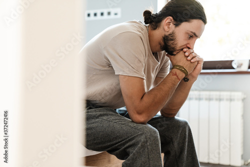 Young man in depression sitting on bed
