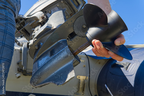 man changing propeller on outboard motor. Repairing outboard motor for boat, replacing screw.