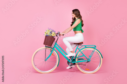 Full size profile side photo of positive cheerful girl ride retro bicycle collect field wild flowers wear green white outfit isolated over pastel color background © deagreez