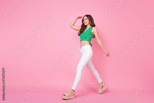 Full length profile side photo of positive cheerful girl hold hand look forward want see her friend wear lifestyle clothes isolated over pink color background © deagreez