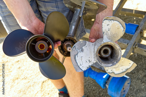 man changing propeller on outboard motor. Repairing outboard motor for boat, replacing screw. photo