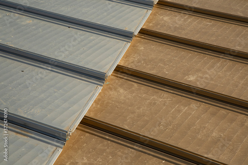 Metallic aluminum sheets in steel and gold color on the roof. close-up