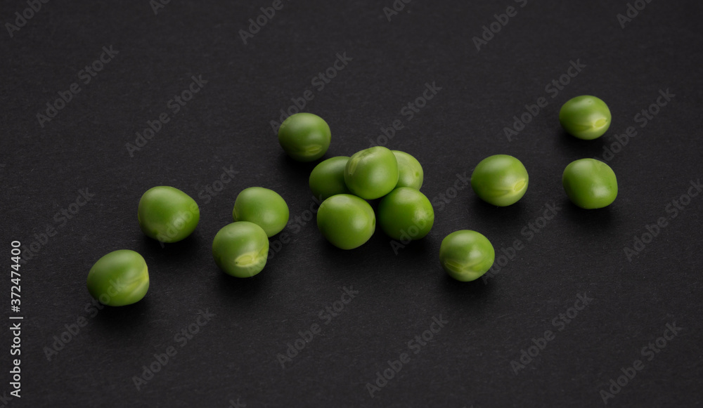 Pile of green peas on black background