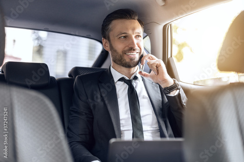 Happy successful businessman talking on phone in car © Prostock-studio