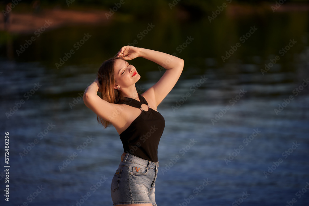woman in black tank top and denim shorts on the beach. teenager girl on the lake. woman in black tank top and denim shorts on the beach. teenager girl on the lake.