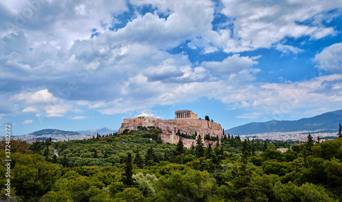 View of Acropolis hill and theater of Odeon in Athens  Greece from the hill of Philoppapos or Muses in summer daylight with great clouds in blue sky.