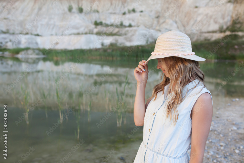 Portrait of beautifull woman  in a hat near a lake with light water and sandy hills. Good  vew on natural landscape