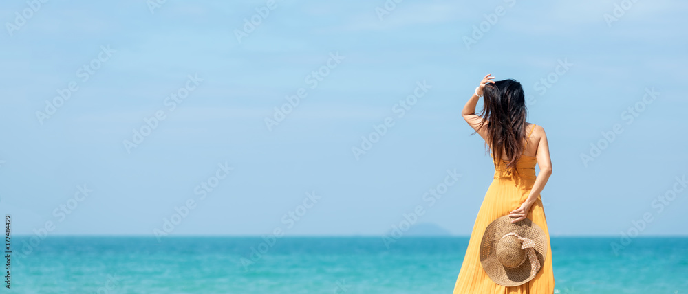 Summer vacations. Lifestyle woman relax and chill on beach background.  Asia happy young people wearing yellow dress fashion summer trips walking enjoy  tropical beach.  - obrazy, fototapety, plakaty 