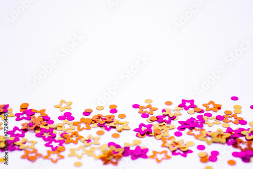 Scattered round confetti and in the form of flowers pink, gold and orange color on a white background. Copy space. Spring and summertime, birthday and wedding concept