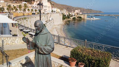 statua di Padre Pio con lo sfondo del borgo antico photo