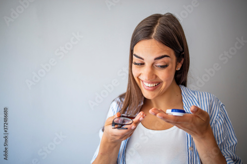 Girl Comparing Contacts to Eyeglasses for Vision Correction. Woman choosing between contact lenses and glasses in optic store. Woman Thinking to Choose Contact Lenses Over Eyeglasses