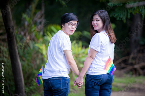 LGBTQ Lesbian Couple ,Two friends in casual wear standing and laughing together. Best friends enjoying on the green field in the morning. © NITIKAN T.