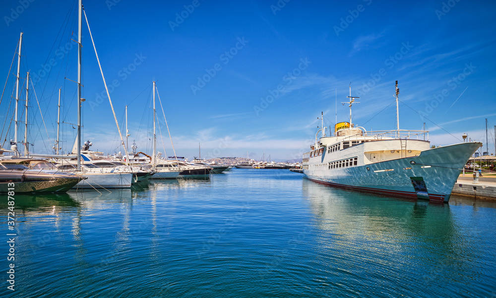 Boats and yachts anchored or moored in Athens marina and by its promenade in Glyfada on a bright summer day. Athens, Greece