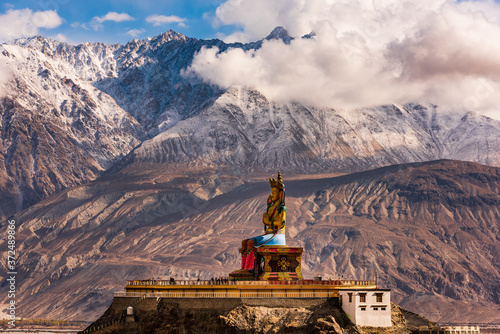 The Maitreya Buddha statue with Himalaya mountains in the background from Diskit Monastery or Diskit Gompa, Nubra valley, Leh Ladakh