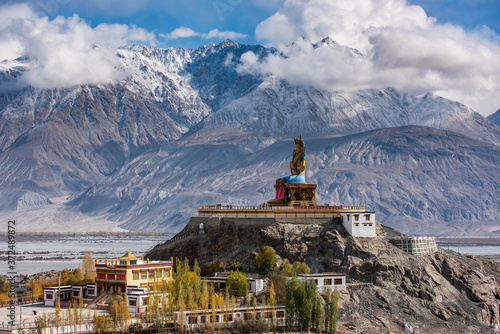 The Maitreya Buddha statue with Himalaya mountains in the background from Diskit Monastery or Diskit Gompa, Nubra valley, Leh Ladakh photo