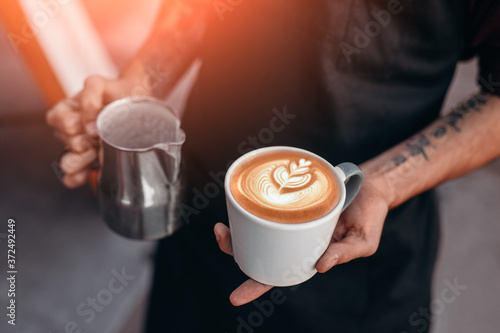 Barista holding cup of coffee with latte art