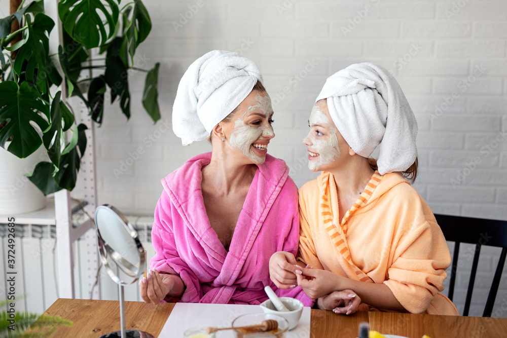 Mother and her daughter put natural musk on face for better skin and towels on head Mother and her daughter put natural musk on face for better skin and towels on head
