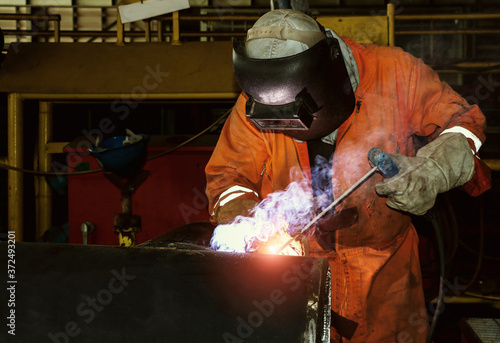 Metal workers use manual labor, skilled welder, factory workers making, welder is welding the steel pipe in factory, welding fumes, the welder standing to weld iron in vintage tone.