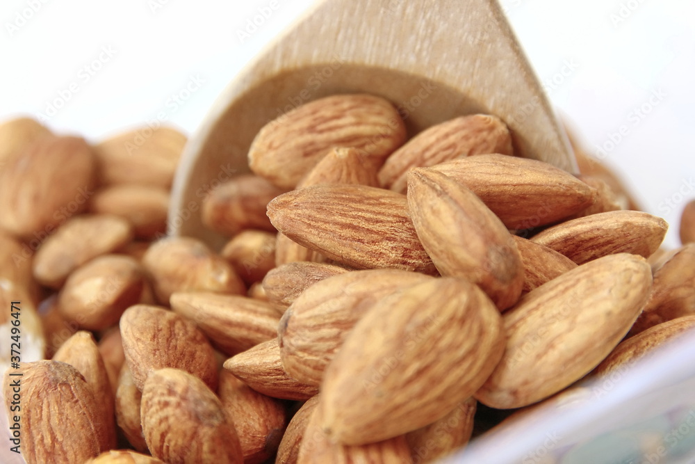 close up roasted organic brown almond seed on wooden spoon. close up roasted organic brown almond seed on wooden spoon.