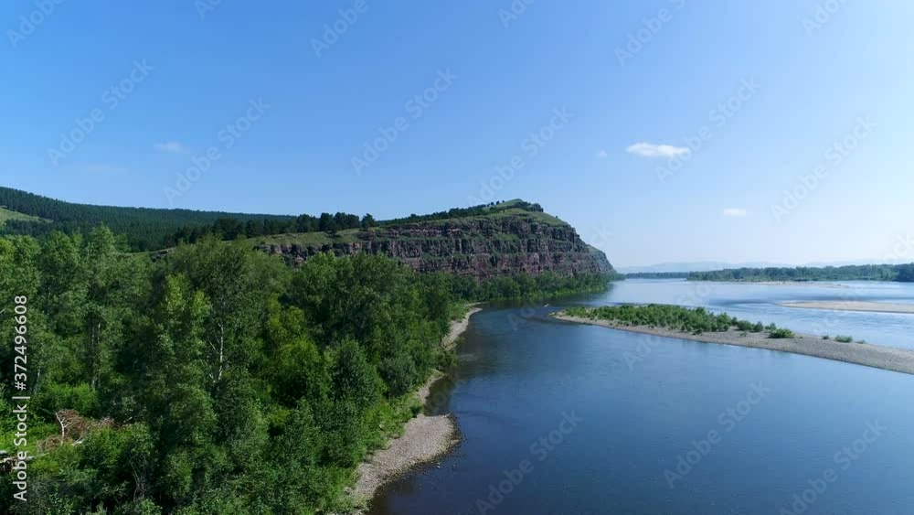 A drone flies over a river on a sunny day, next to a high cliff, Russia, Siberia, Khakassia. A drone flies over a river on a sunny day, next to a high cliff, Russia, Siberia, Khakassia.