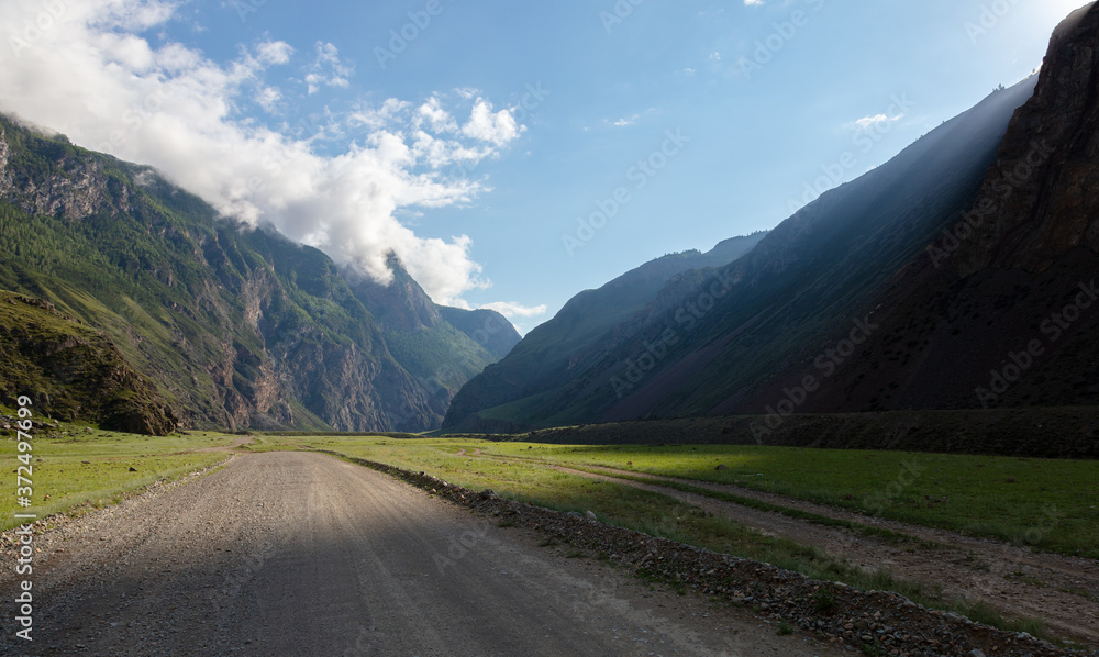 a canyon with a dirt road among the fjords. a ray of light illuminates a gorge in a beautiful mountain valley.
