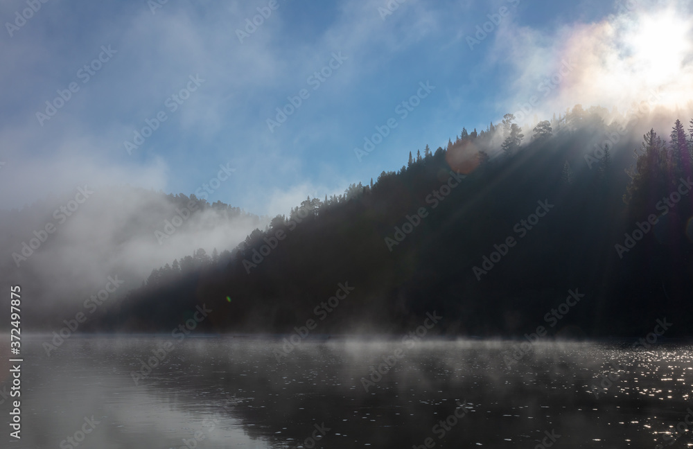 fjords in the morning fog on the lake. fantastic morning in the Siberian taiga with bright sun, fog and thick fog on the river