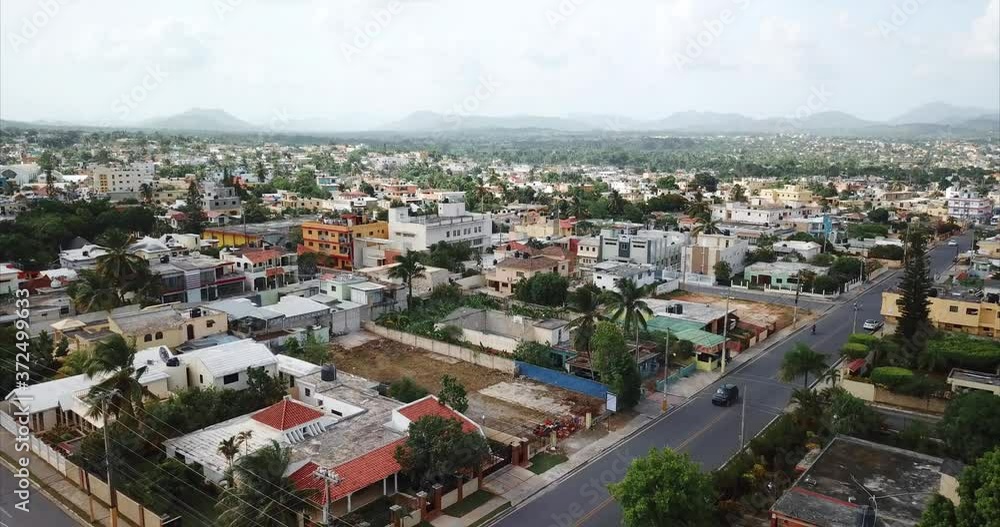 Aerial view of a latin american city Higuey, Dominican Republic. High-rise buildings of a residential area and palm trees on the street Aerial view of a latin american city Higuey, Dominican Republic. High-rise buildings of a residential area and palm trees on the street