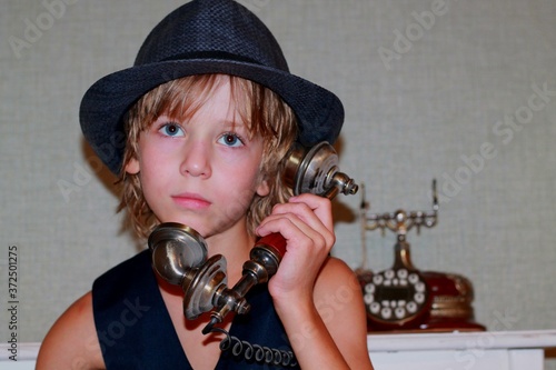Wallpaper Mural 
A child with blond hair, a blue straw hat, and a vintage telephone. Torontodigital.ca