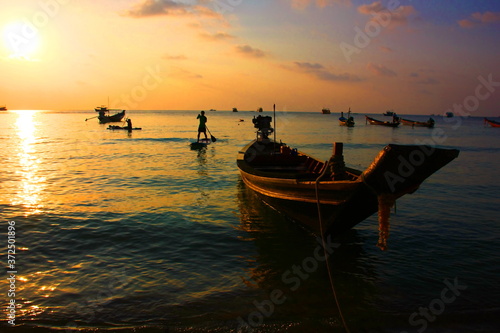 tourist are enjoy with surf board on sea in evening time before sun set.silhouette group of people in relax time with seascape,cloud sky nature background.