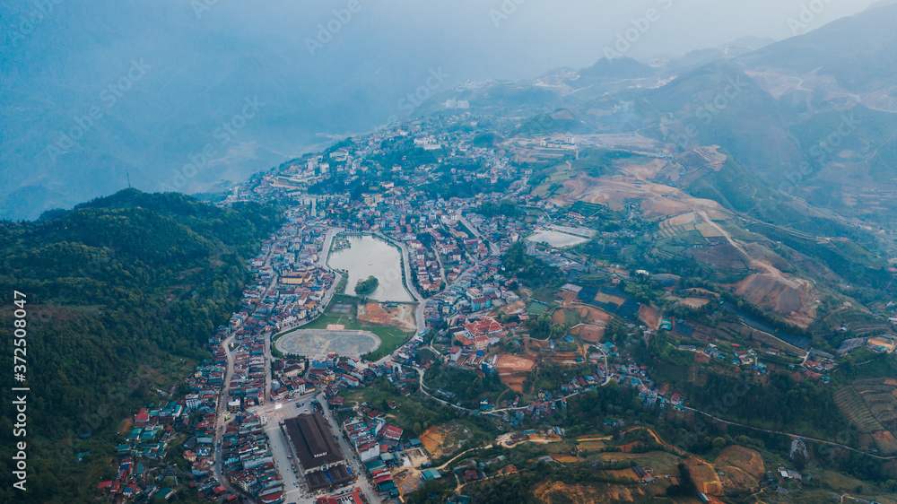 Obraz premium Aerial view of panorama landscape at the hill town in Sapa city, Vietnam with the sunny light and sunset, mountain view in the clouds