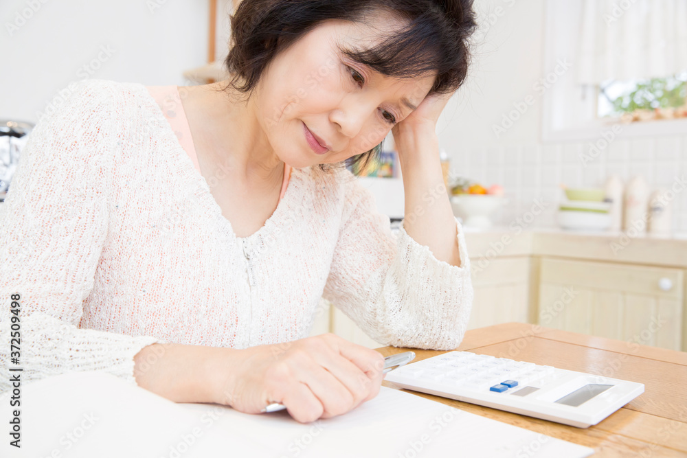家計簿をつけるシニア女性