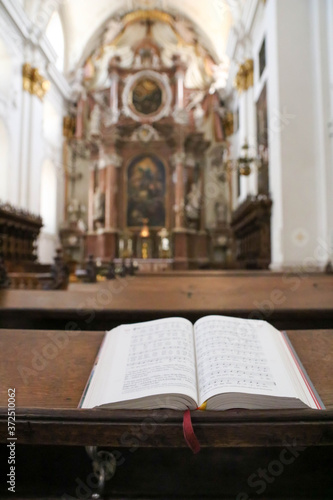 Bible or prayer book lying on praying bench in catholic church, selective focus. Vertical