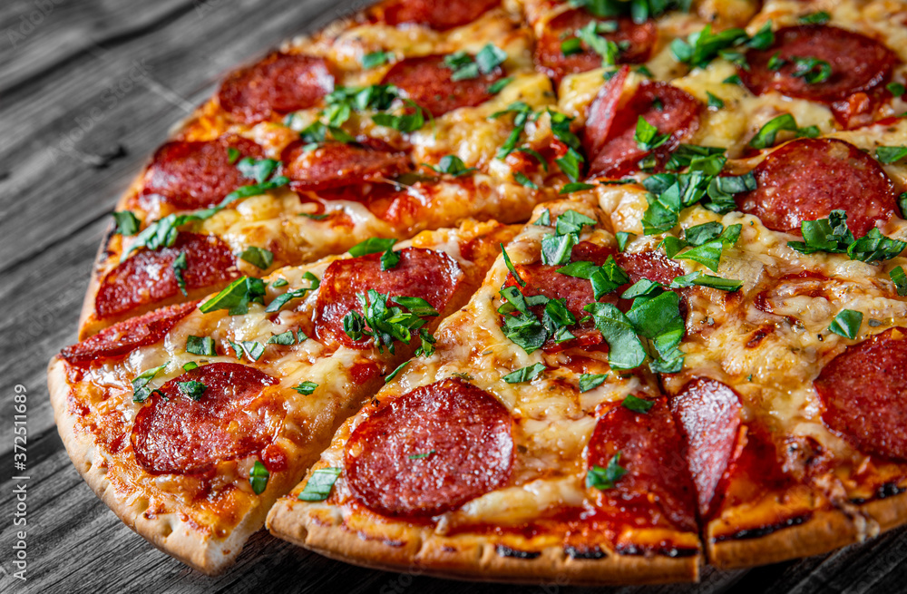 Pepperoni Pizza with Mozzarella cheese, salami, Tomato sauce, pepper, Spices and Fresh basil. Italian pizza on wooden table background Pepperoni Pizza with Mozzarella cheese, salami, Tomato sauce, pepper, Spices and Fresh basil. Italian pizza on wooden table background
