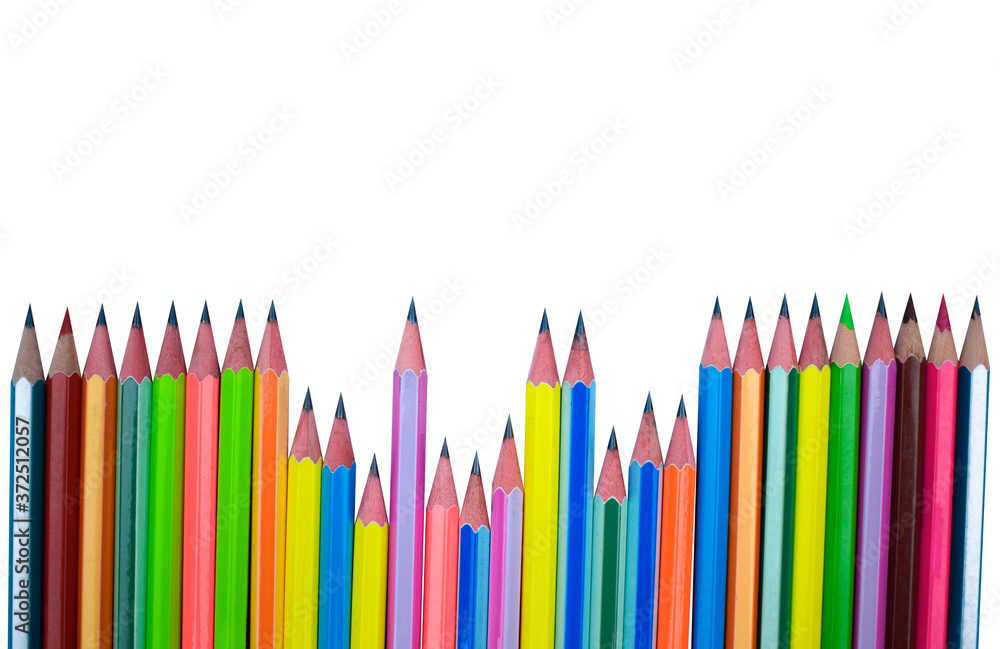 Scattered line of different colored wood pencil crayons placed on a white paper background Scattered line of different colored wood pencil crayons placed on a white paper background