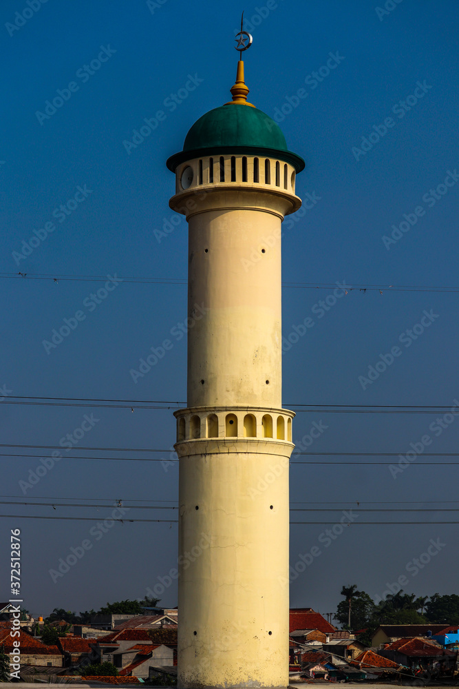 The mosque's green domed minaret is isolated by the blue sky.