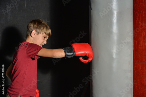 A teenage boy angrily punches a sports bag in the gym. © andov