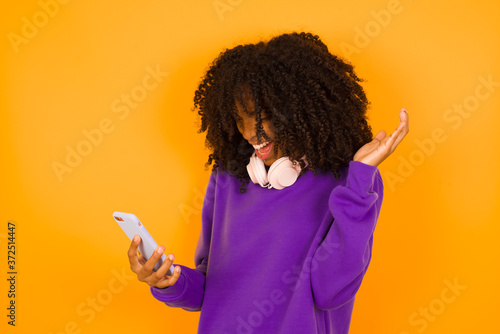 Excited woman showing smartohone blank screen, blinking eye and doing ok sign with hand. Studio shot of shocked girl holding smartphone with blank screen. Advertisement concept. photo