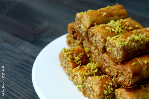 Closeup Pile of Mouthwatering Baklava Pastries with Pistachio Nuts on a White Plate