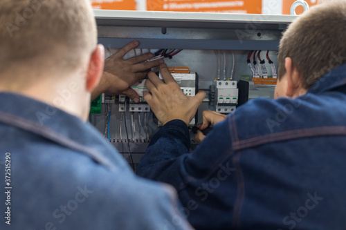 Industrial production of an electricity panel boards - two men workers doing something with opened board