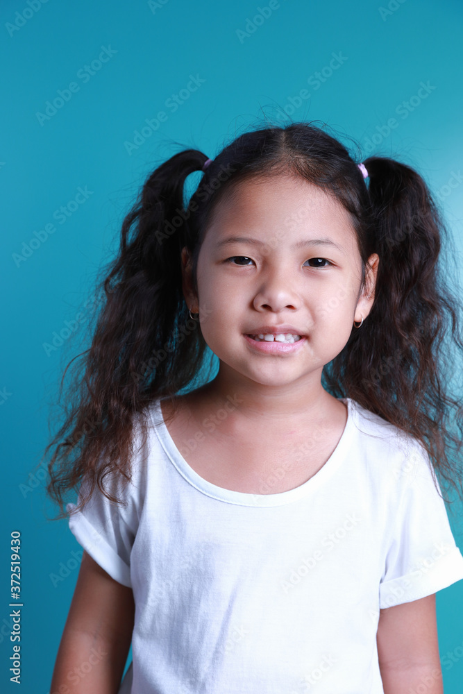 Asian little kid girl smile happiness portrait looking at the camera on green background.
